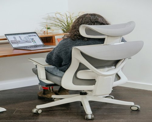A person standing up and stretching near an office chair