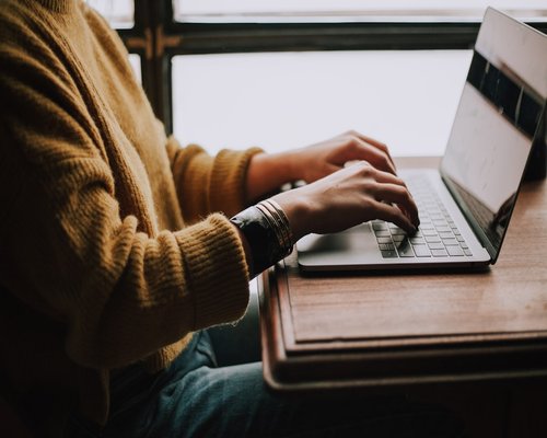 A person typing on a laptop in a cozy home environment